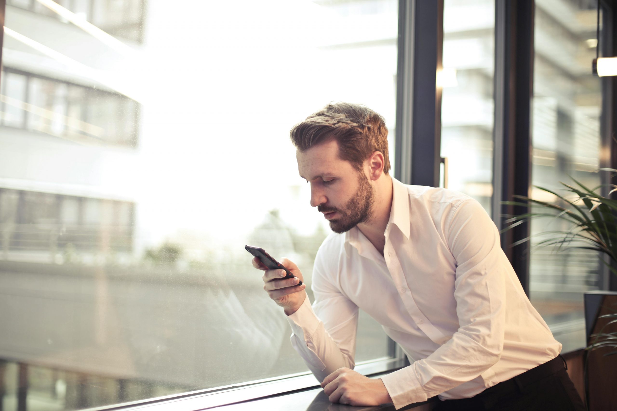 Ein Mann sitzt und schaut auf sein Smartphone.